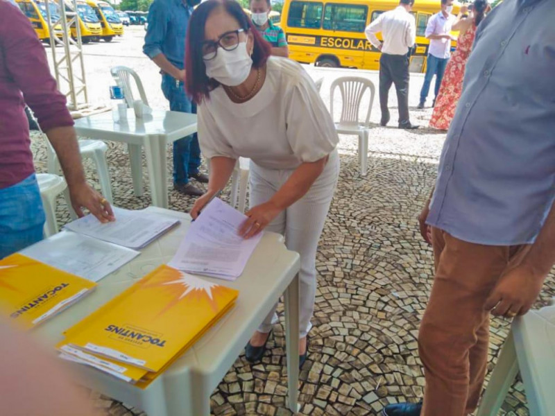 Prefeita Maria Aparecida assinando documentos para recebimento do ônibus escolar.